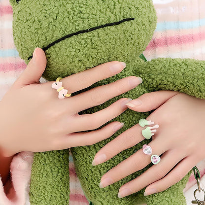 Elegant female hands with stylish rings embracing a plush green frog, showcasing beautiful manicured nails against a cozy, colorful backdrop. Perfect for fashion and accessory themes. #FashionAccessories #StylishRings #Manicure #PlushToys #TrendyLook #ComfortStyle